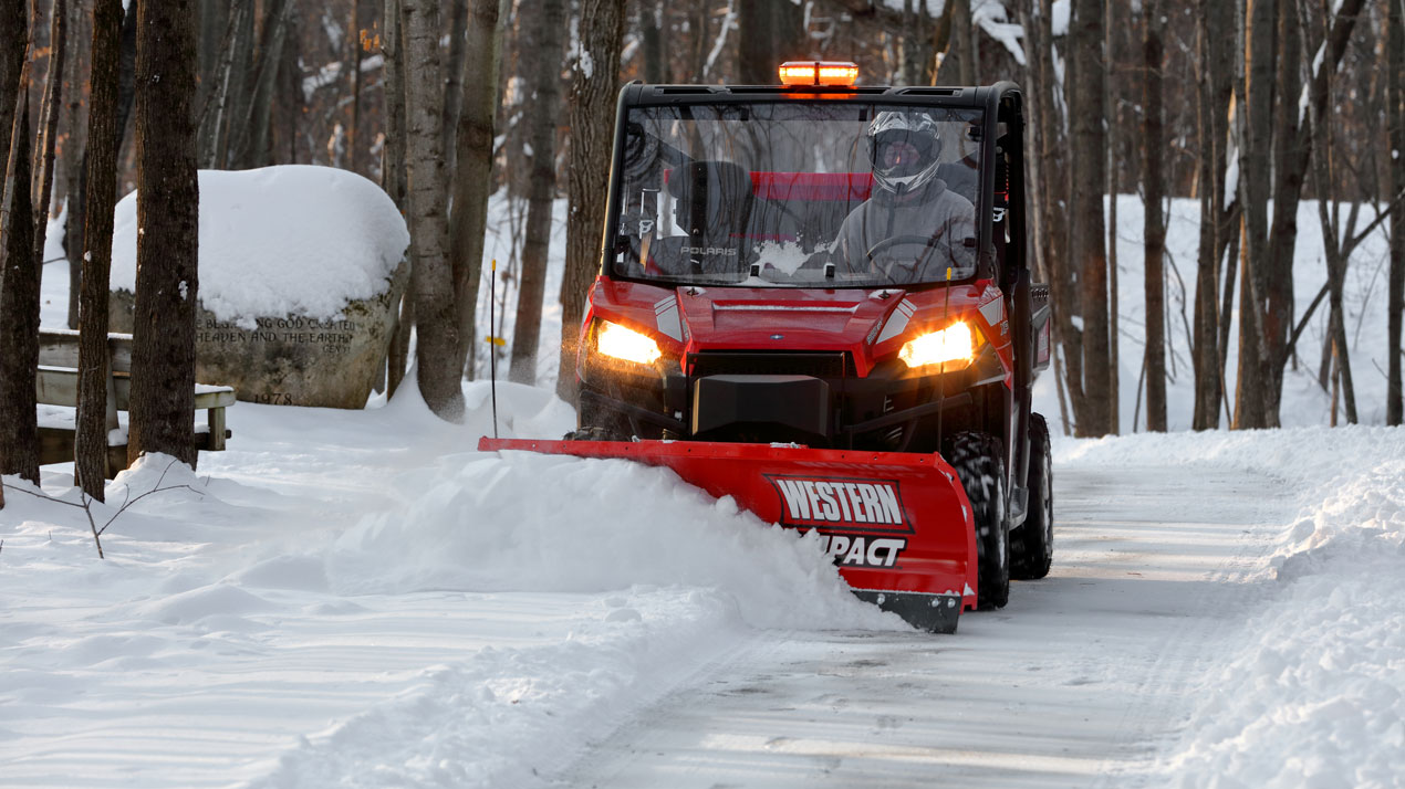 Employee operating UTV plow